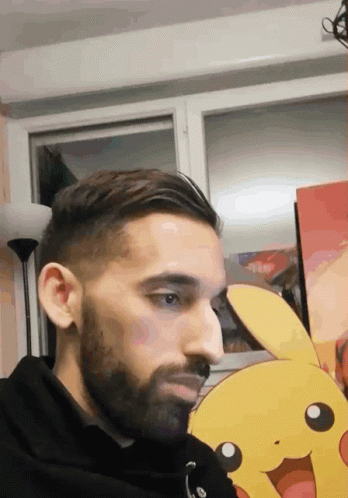 a man with a beard is standing in front of a pikachu picture