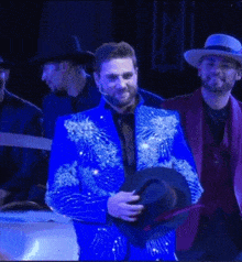 a man in a blue suit holds a hat