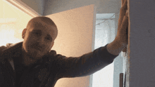a man is leaning against a wall with his hand on it
