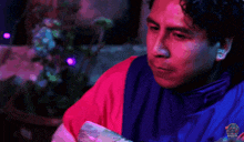 a man in a red and blue jacket is holding a piece of money