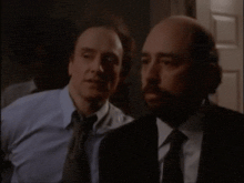two men are standing next to each other in a dark room .