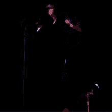 a man in a purple jacket is singing into a microphone on stage .