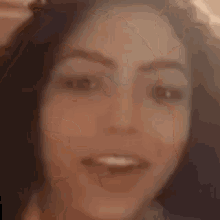 a close up of a woman 's face smiling and looking at the camera .