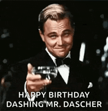 a man in a tuxedo is holding a glass of champagne .