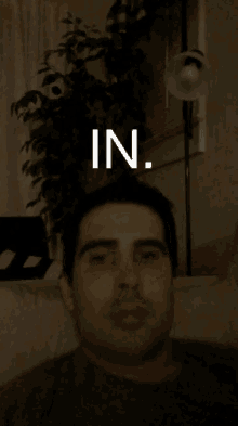 a man sitting in a dark room with the word in on his face