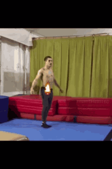 a man without a shirt is doing a trick on a blue mat