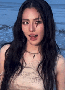 a woman with long black hair and a necklace with a cross on it