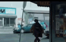 a man is walking down a street in front of a store that has a sign that says ' m ' on it