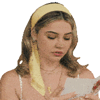 a woman wearing a yellow headband looks at a card
