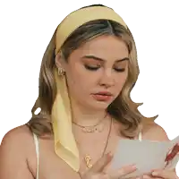a woman wearing a yellow headband looks at a card