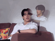 a man in a white shirt is laying on a couch with a watch on his wrist