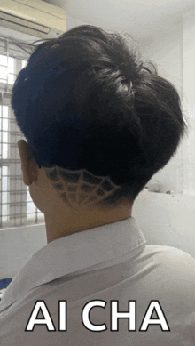 a man with a shaved design in his hair has ai cha written on his shirt