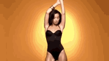 a woman in a black swimsuit is dancing with her hands in the air .