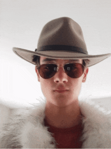 a man wearing a hat and sunglasses with a fur coat