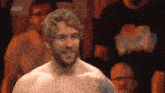 a shirtless man stands in front of a crowd with aew written on the bottom right corner