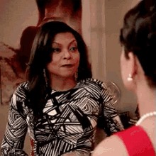 a woman in a black and white striped dress is talking to another woman .