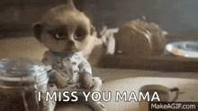 a meerkat doll is sitting on a table with the words `` i miss you mama '' written next to it .