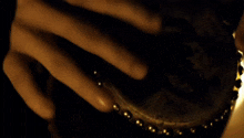 a person is playing a drum with gold beads on it