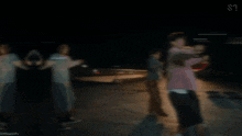 a group of people dancing in a dark room with a s on the bottom right