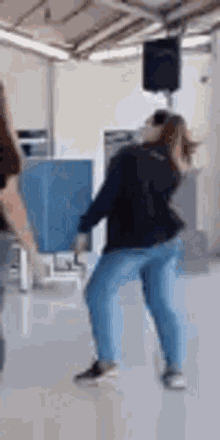 a woman in blue jeans is dancing in a room .