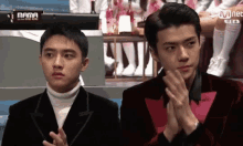 two men are sitting next to each other with their hands folded in front of a sign that says mama