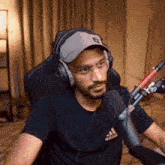a man wearing headphones and a hat is sitting in front of a microphone in a room .