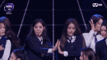 a group of girls are performing in front of a mnet advertisement