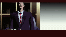 a man in a suit and tie stands in front of a bookshelf