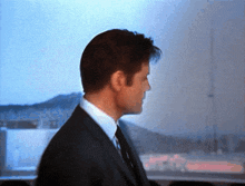 a man in a suit stands in front of a window