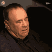 a man in a suit sits in the back seat of a car with bar rescue written on the screen