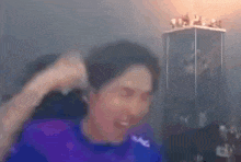 a blurry picture of a man in a purple shirt holding his fist up in the air .