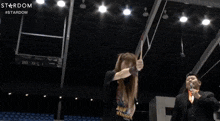 a man in a suit is standing in a stadium with a stardom logo on the bottom