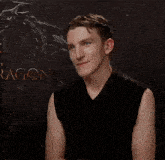 a man with his arms crossed is standing in front of a dragon poster