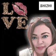 a woman wearing sunglasses stands in front of a love sign