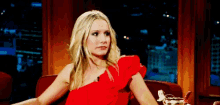 a woman in a red dress is sitting in a chair