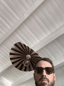 a man wearing sunglasses stands in front of a light fixture
