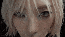 a close up of a woman 's face with blonde hair and blue eyes looking at the camera .