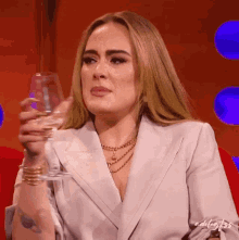 a woman in a white suit holds a glass of wine in her hand