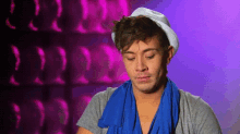 a man wearing a white hat and a blue scarf is looking down