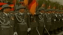 a group of soldiers are standing in a line in front of a flag .