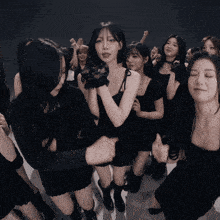 a group of young women in black dresses are dancing together