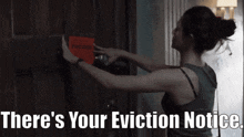 a woman is putting a red sign on a door that says " there 's your eviction notice "