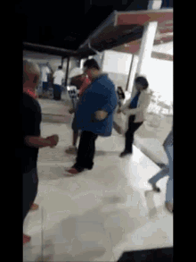 a group of people are standing on a white tiled floor in a room .