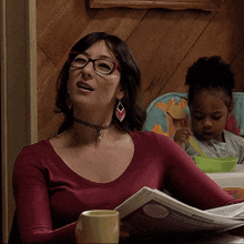 a woman sitting at a table reading a newspaper while a little girl sits in a high chair