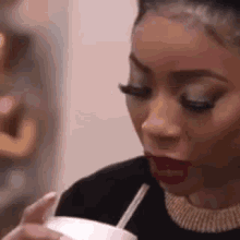 a woman is drinking through a straw from a cup .