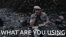 a man sitting on a rocky beach with the words what are you using written below him