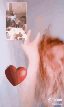 a tiktok video of a person 's hand with a red heart on it