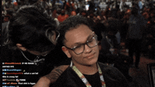 a man wearing glasses is being kissed by another man in front of a crowd of people