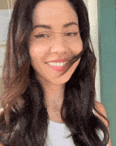 a woman with long dark hair is smiling with her hair blowing in her face