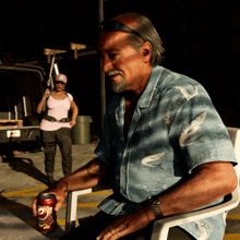 a man sits in a chair with a can of dr pepper in his hand